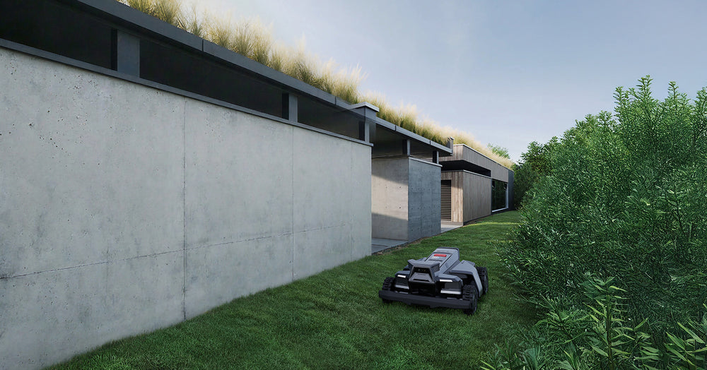 Navimow i110E robot lawn mower mows grass near concrete building.