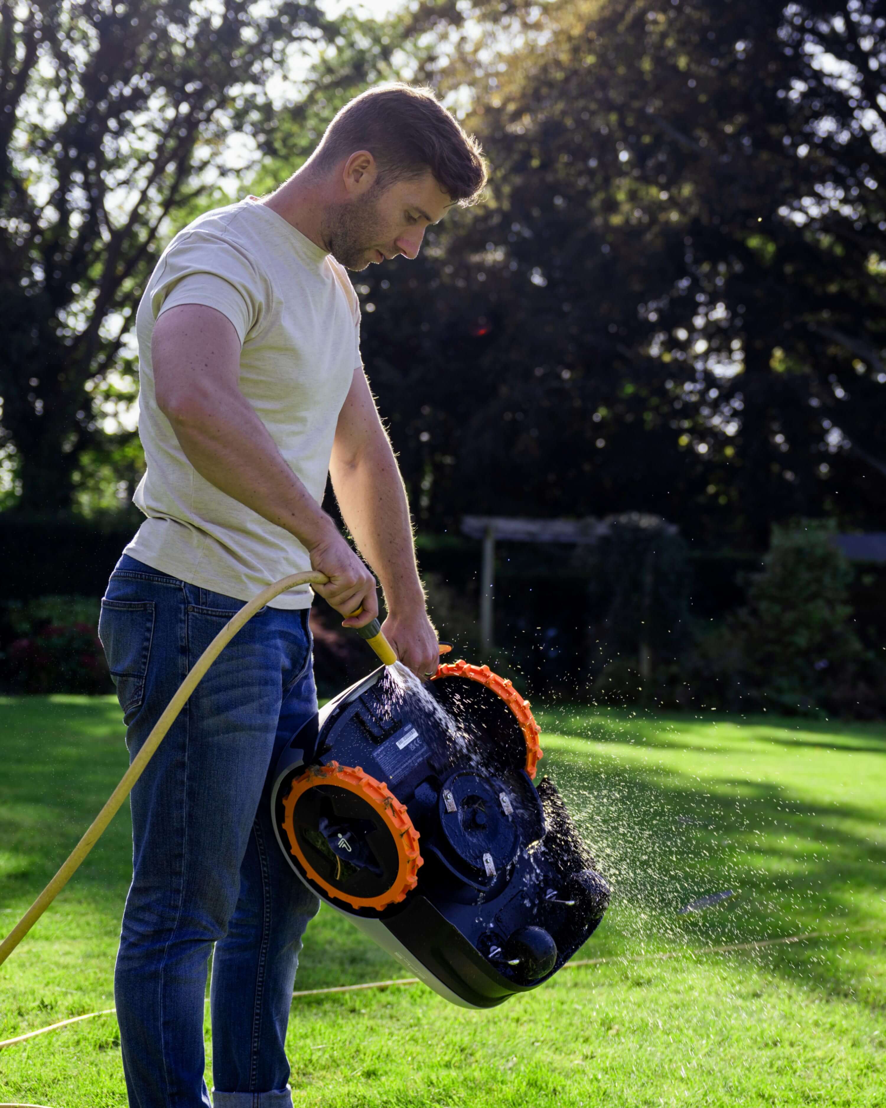 Navimow i105E robot lawn mower being washed by a man.