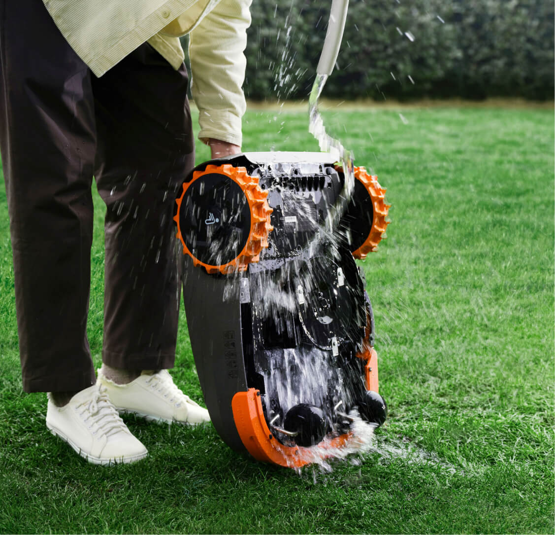 A man is washing a Navimow i110N robot lawn mower.