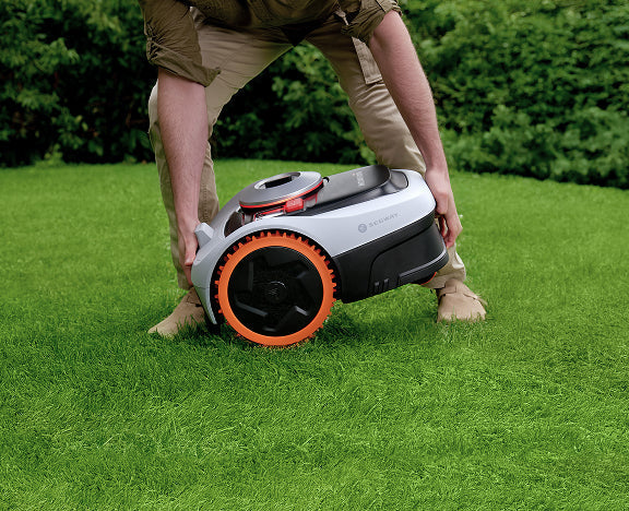 A man lifting a Segway Navimow i110N robot lawn mower.