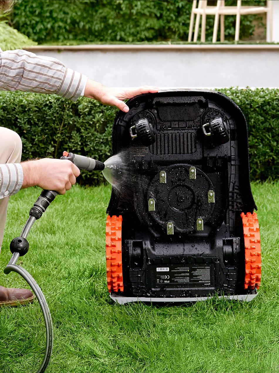 Navimow i105E robot lawn mower is being washed by person.