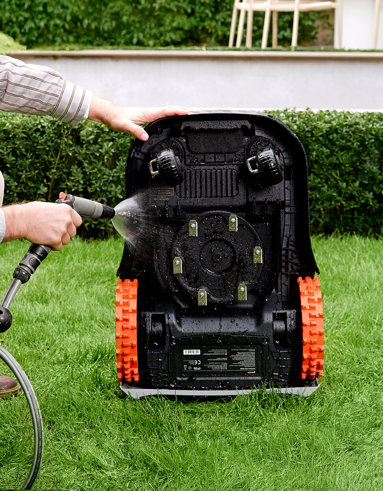 Navimow i110E robot lawn mower is being washed with water.