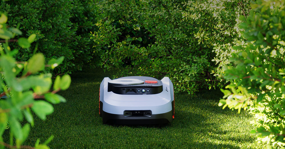 Navimow i110E robot lawn mower in a lush green garden.
