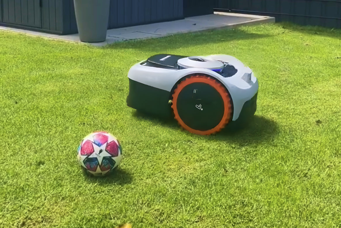 Navimow i110N robot lawn mower on grass with soccer ball.