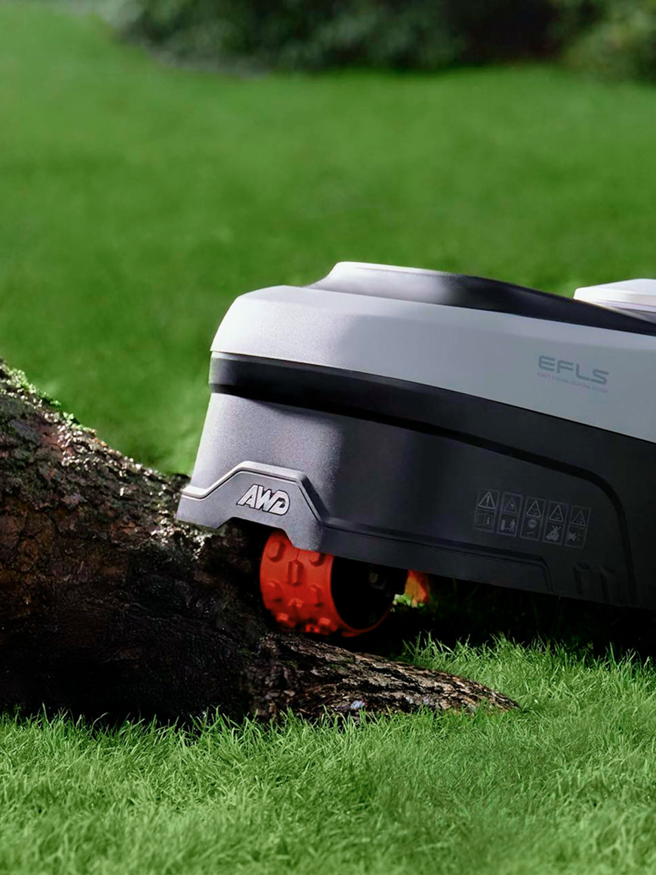 Navimow i110E robot lawn mower climbing over a tree root.